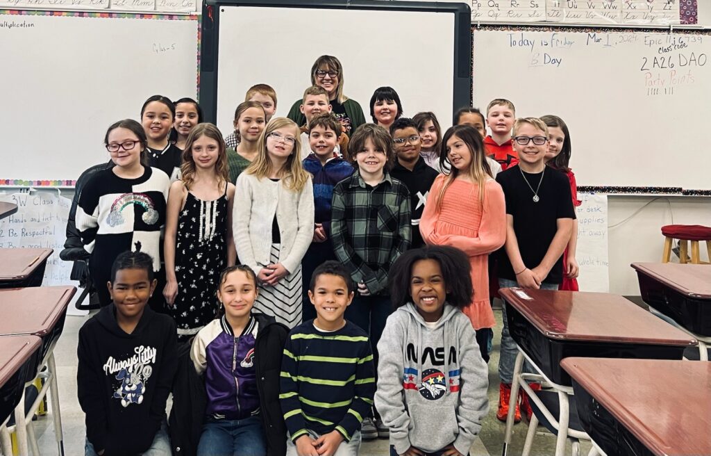 Paraeducator Kate Bonar poses for a photo with a group of smiling students