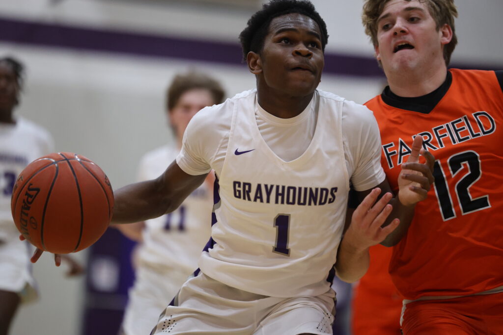 A member of the boys basketball team dribbles the ball while fending off a guard on the opposing team.