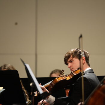 A student plays a violin during an orchestra concert.