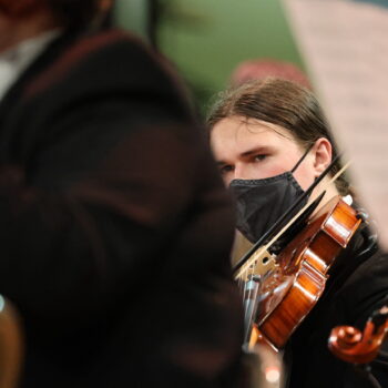 A student plays a violin during an orchestra concert.