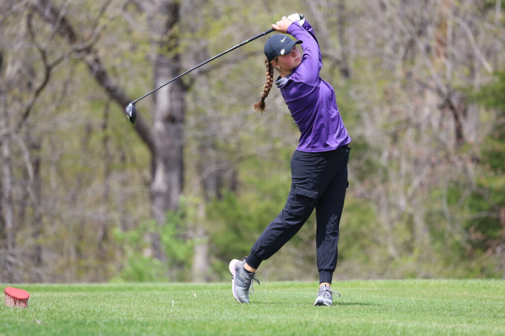 A member of the girls golf team swings a club during a golf tournament