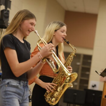 A girl laughs while holding a trumpet and another plays the saxophone during SoloFest.