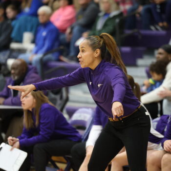 Coach Adriana Mafra signals to her players during a basketball game.