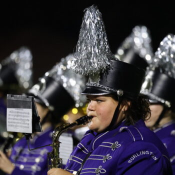 A student plays the saxophone with the marching band during a football halftime show.