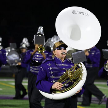 A student plays the tuba with the marching band during a football halftime show.