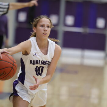 A member of the girls basketball team dribbles a ball across the court