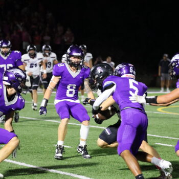 Football players go to take down a member of the opposing team.