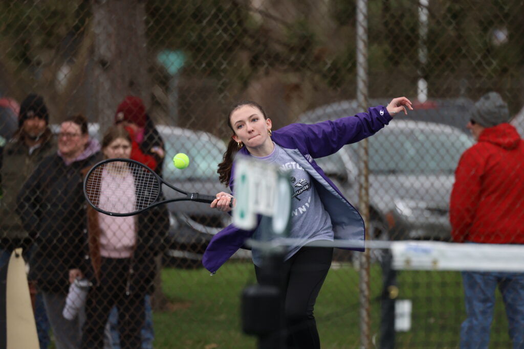 A member of the BHS girls tennis team goes to whack a tennis ball with her racket.