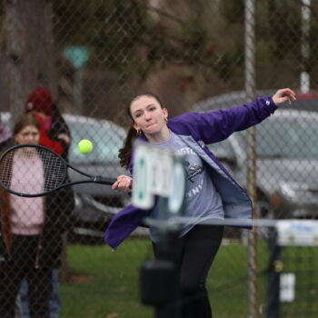 A member of the BHS girls tennis team goes to whack a tennis ball with her racket.