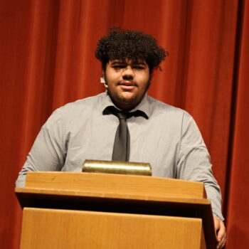 A student actor stands behind a podium during the fall production of 