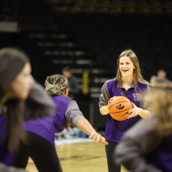 A member of the BHS girls basketball team smiles while holding a ball during a scrimmage with her teammates at Carver-Hawkeye Arena in Iowa City. She had just met Caitlin Clark.