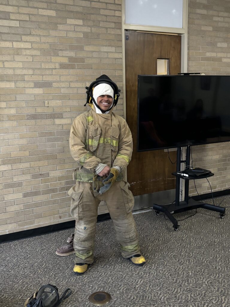 Dimitri Donald, a Burlington High School student who was elected president of the school’s IJAG program, tries out firefighting gear Wednesday, March 6, during Western Illinois University’s Law Enforcement Justice Administration Open House. Donald was among more than 50 BHS students to attend the career exploration event.