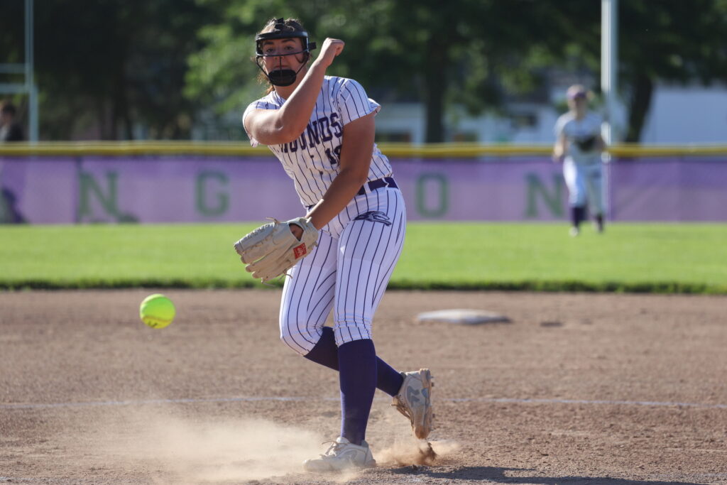 A pitcher rocket throws a softball to a batter on the ball field from the pitcher's mound. 