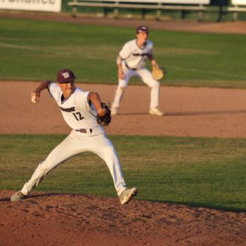 A pitcher winds up a pitch on the pitcher's mound during a baseball game.