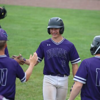 A baseball player high-fives his teammates following an inning during a baseball game.