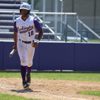 A baseball player begins to make his way to first base during a baseball game.