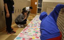 Eighth-graders decorate a GEAR UP banner with painted handprints Sept. 24, 2024, at Edward Stone Middle School.