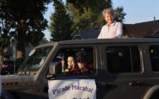 Homecoming Parade Grand Marshal Geane Cleland looks at paradegoers lined up along West Avenue from the sun roof of a Jeep Rubicon being driven by Amy Kristensen Sept. 19, 2024, en route to Burlington High School.