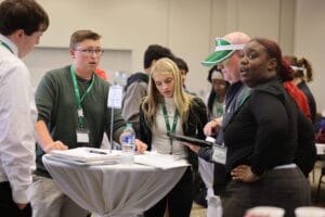 Four Burlington High School students consult a trader during the Junior Achievement Stock Market Challenge.