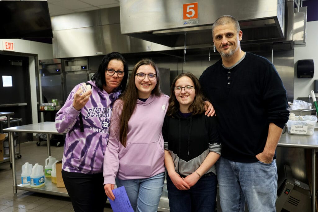 ennifer Moore poses for a photo with her daughters, Kaylee and Raylee Moore, and husband, Nathan Moore, while enjoying a cookie Tuesday, April 22, 2025, in the culinary classroom at Burlington High School.