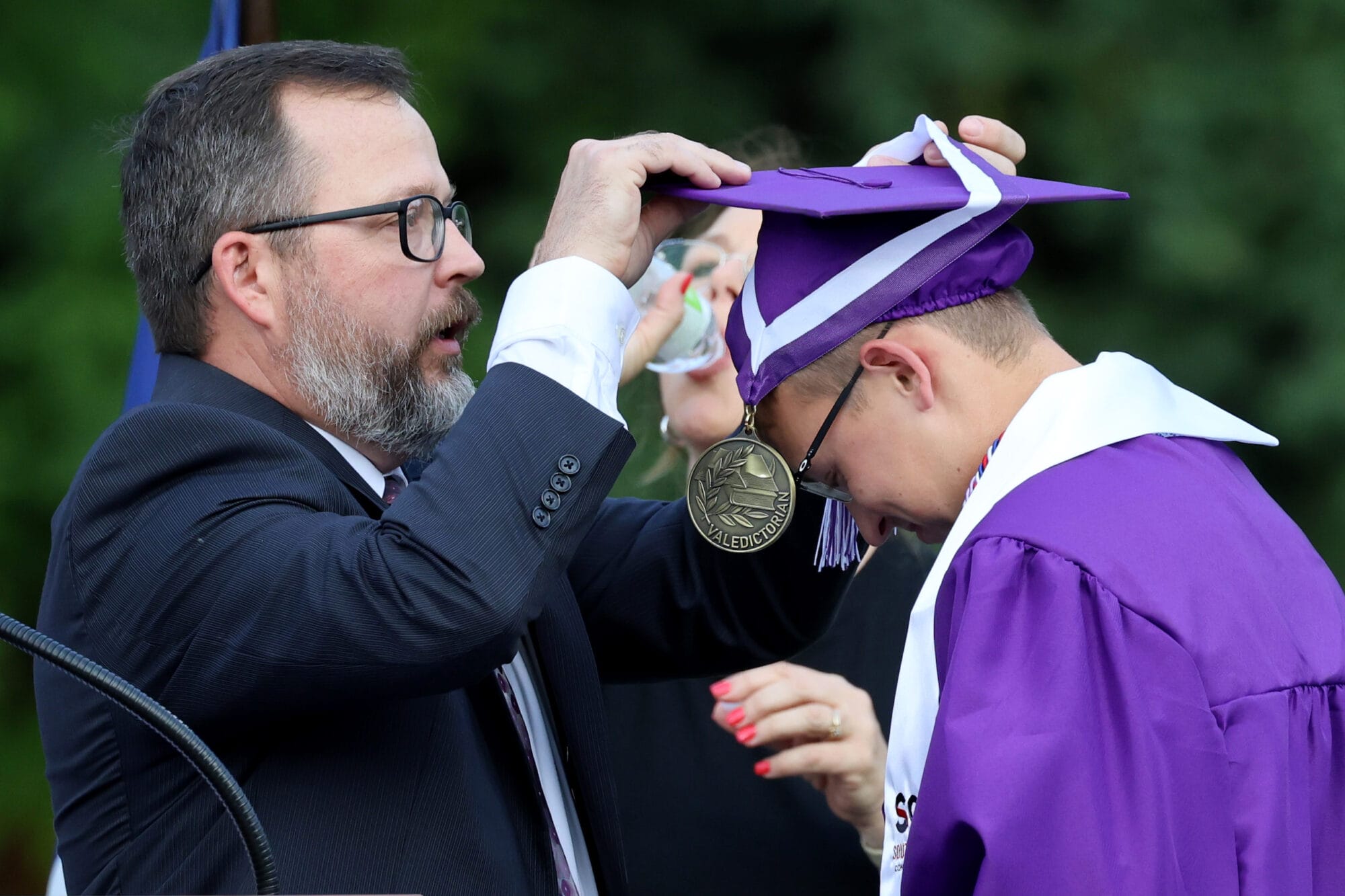 Burlington High School Principal Nathan Marting presents William Woodard with a Valedictorian medal during Burlington High School's 2025 commencement ceremony at Bracewell Stadium.
