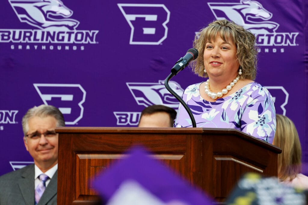 Burlington School Board President Anika McVay stands behind a podium while making a speech during Burlington High School's 2025 commencement ceremony at Bracewell Stadium.