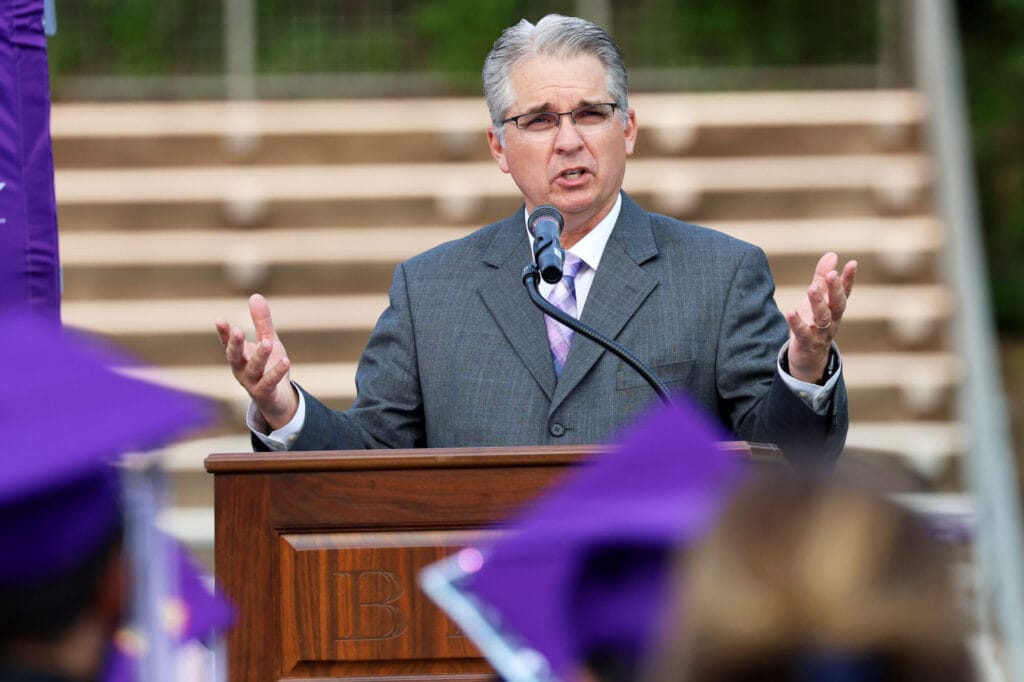 Superintendent Robert Scott stands behind a podium while making a speech during Burlington High School's 2025 commencement ceremony at Bracewell Stadium.