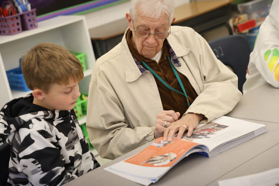 Longtime volunteer Fred Chandler and a student follow along in a textbook Thursday, Nov. 16, in Lori Johnson’s fourth grade classroom at Black Hawk Elementary School.