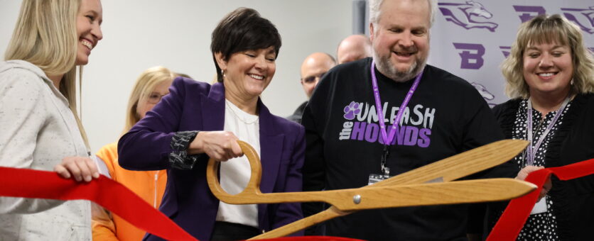 Former BHS principal Monica Myers, flanked by three school board members, uses a large pair of scissors to cut a ribbon during a ribbon cutting ceremony for the school's new science wing.