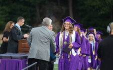 The salutatorian shakes hands with a school board member after accepting her diploma during the 2024 commencement ceremony at Bracewell Stadium.