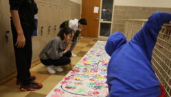 Eighth-graders decorate a GEAR UP banner with painted handprints Sept. 24, 2024, at Edward Stone Middle School.