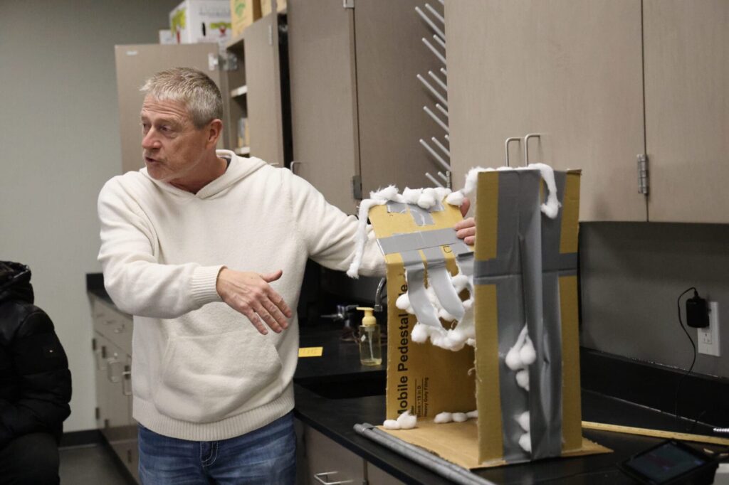 Science teacher Brian Blake shows his Physical Science class a chest protector that was designed and built by a student in another class that wound up becoming more effective in reducing force after it broke in a way that created a springboard effect.