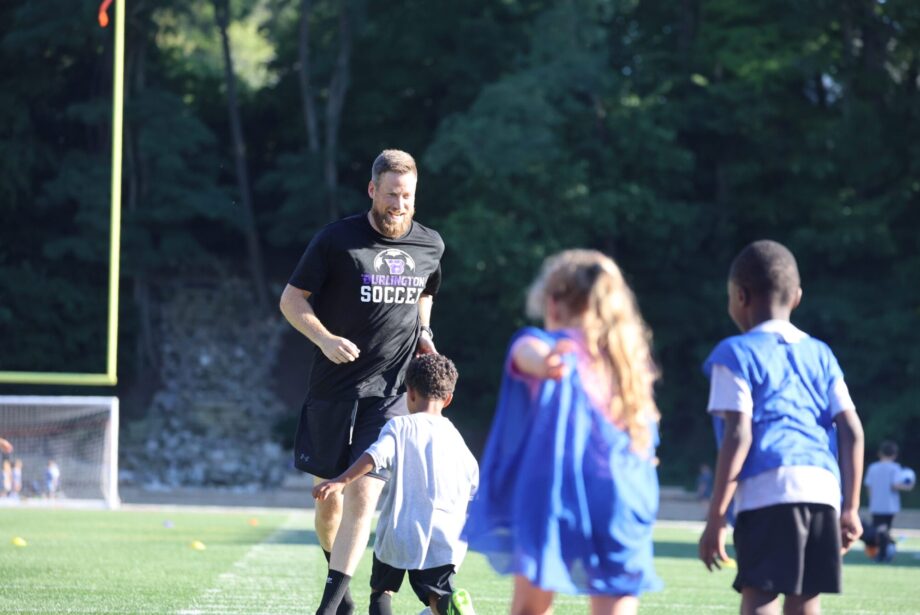 Trevor Cushman is chased by children during a soccer drill June 26, 2024, during Grayhound Soccer Camp at Bracewell Stadium. Trevor, a 2004 graduate of Burlington High School, is carrying on his father’s legacy as the new head coach of the Burlington High School boys soccer team.