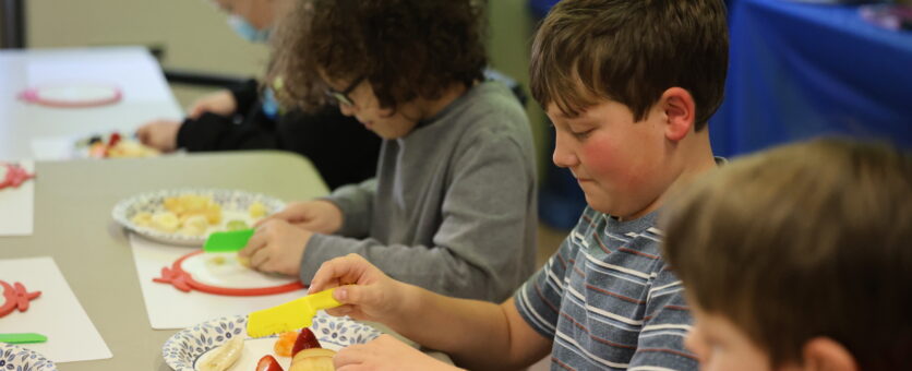 A boy cuts up different fruits to make fruit art