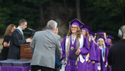 The salutatorian shakes hands with a school board member after accepting her diploma during the 2024 commencement ceremony at Bracewell Stadium.