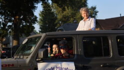 Homecoming Parade Grand Marshal Geane Cleland looks at paradegoers lined up along West Avenue from the sun roof of a Jeep Rubicon being driven by Amy Kristensen Sept. 19, 2024, en route to Burlington High School.