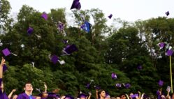 Purple caps fly up in the air as graduates face the crowd at the close of Burlington High School's 2025 commencement ceremony at Bracewell Stadium.