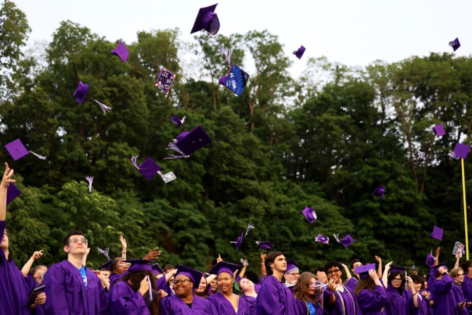 Purple caps fly up in the air as graduates face the crowd at the close of Burlington High School's 2025 commencement ceremony at Bracewell Stadium.