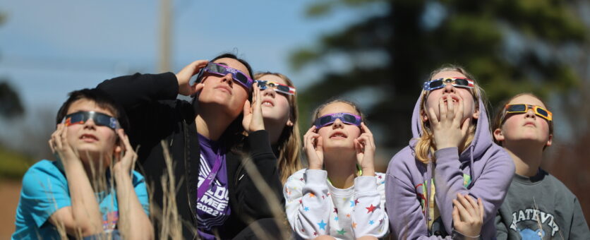 A teacher and five students watch the eclipse from the outdoor classroom at Aldo Leopold Intermediate School