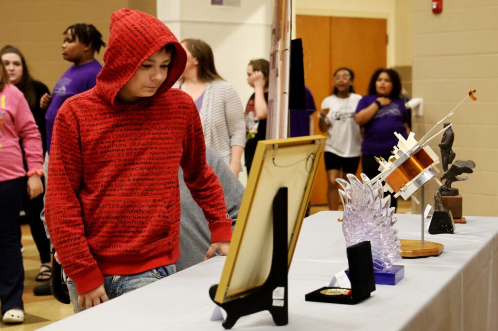 Edward Stone Middle School students look at items donated to the school by the family of the late Dr. Edward Stone Monday, April 28, 2025, in the school auditorium during Student Spotlight. The event featured more than 100 student projects and more than 30 spacecraft models, awards, certificates and other items that once belonged to the former director of NASA’s Jet Propulsion Laboratory.