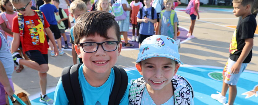 Two friends pose side-by-side for a photo on the first day of school