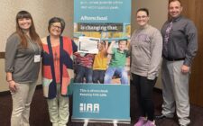 PiECES afterschool program staff and administrators stand on either side of an Iowa Afterschool Alliance banner that reads 