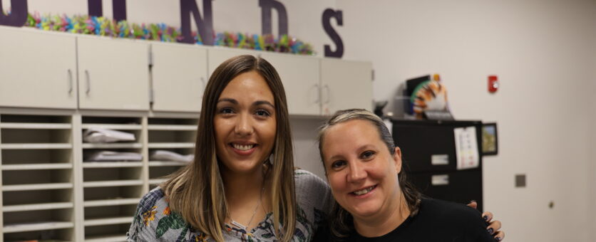 Two office clerks smile for a photo while standing in the office at North Hill