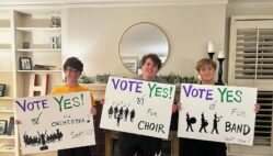 Three former and current Burlington High School students hold signs encouraging voters to cast ballots in favor of a proposed VPPEL increase to fund the expansion of the Aldo Leopold Intermediate School Auditorium. The photo was posted to the BHS Music Boosters Facebook page and is among many posts the boosters made in support of the measure leading up to the special election.