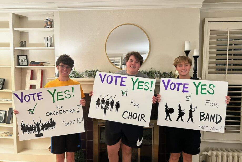 Three former and current Burlington High School students hold signs encouraging voters to cast ballots in favor of a proposed VPPEL increase to fund the expansion of the Aldo Leopold Intermediate School Auditorium. The photo was posted to the BHS Music Boosters Facebook page and is among many posts the boosters made in support of the measure leading up to the special election.