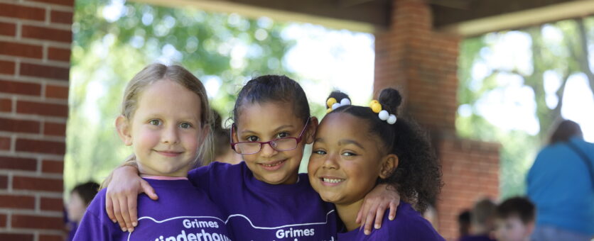 Three girls smile for a photo while out on a field trip at Dankwardt Park