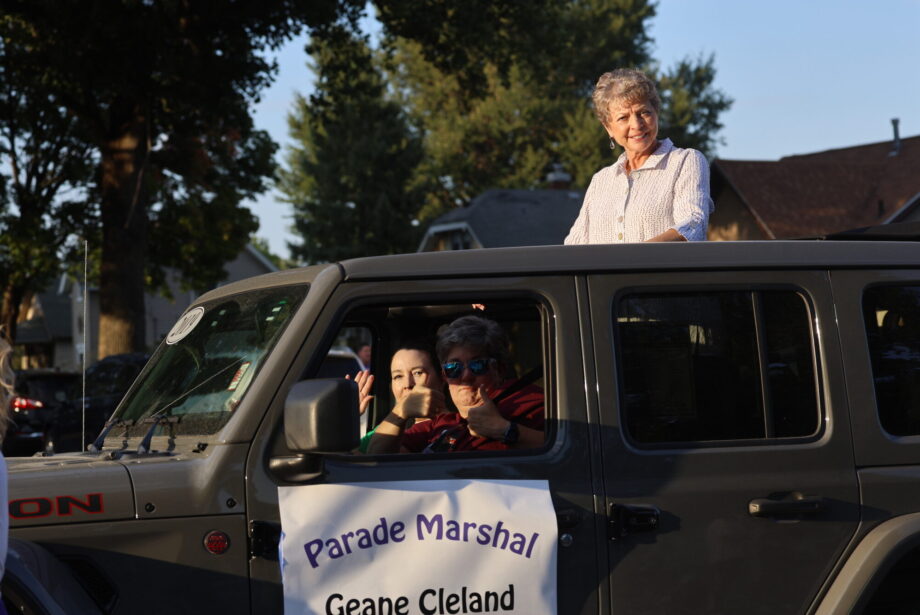 Homecoming Parade Grand Marshal Geane Cleland looks at paradegoers lined up along West Avenue from the sun roof of a Jeep Rubicon being driven by Amy Kristensen Sept. 19, 2024, en route to Burlington High School.