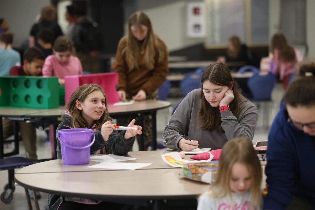 Burlington High School junior Gwendolyn Bilderback and third-grader Kinleigh Dameron draw and color Jan. 15, 2025, in the BHS cafeteria. “Since I want to work with kids as my career path, I really wanted to start with something small and learning from different kids who are different from what I would normally hang out with,” Bilderback said.